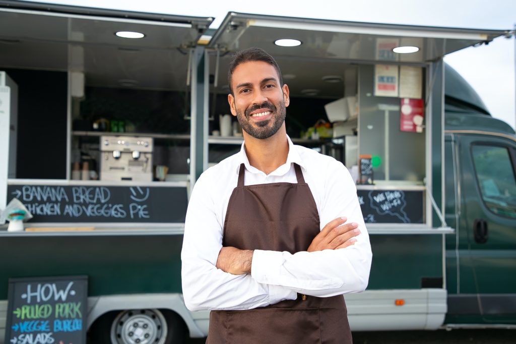 A business owner standing smiling with his arms folded.